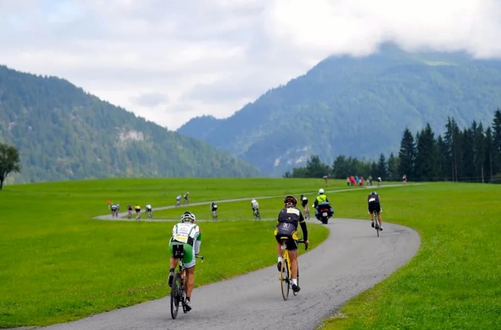 Триатлеты проходят велосипедный этап Challenge Kaiserwinkl-Walchsee на фоне Альп.