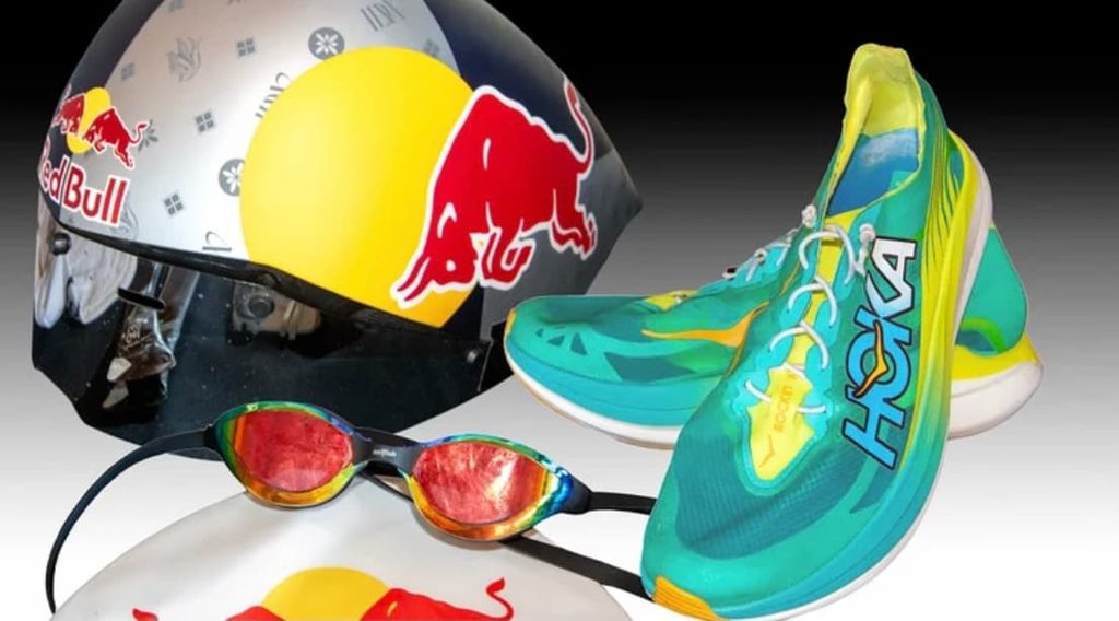 Аэродинамический шлем Red Bull, зеркальные очки для плавания и бирюзовые беговые кроссовки Hoka.